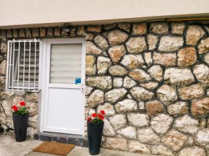 une maison en pierre avec une porte blanche et deux fleurs dans l'établissement Apartment Miris Dunja, à Sarajevo