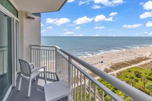 a balcony with a chair and a view of the beach at Stunning Condo with Wall-to-Wall Windows Overlooking Ocean in Myrtle Beach