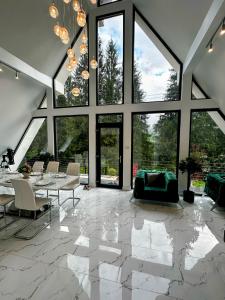 a living room with a table and chairs and large windows at Pine Hill Poiana Marului in Poiana Mărului