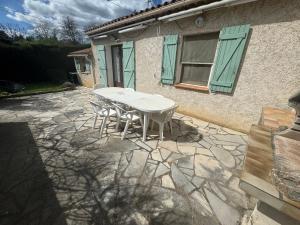 a white table and chairs on a stone patio at La maison des Passereaux in Callian
