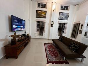 sala de estar con sofá y TV de pantalla plana en Palm715 Villa in jorhat, en Jorhāt