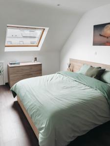 Schlafzimmer mit einem großen grünen Bett und einem Fenster in der Unterkunft Huisaanzee in Ostende