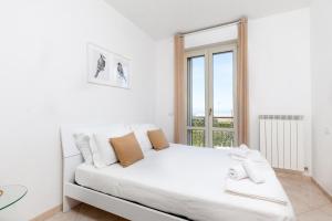 una camera bianca con un grande letto con finestra di MARCHE FULL EXPERIENCE-Apartments a Porto SantʼElpidio