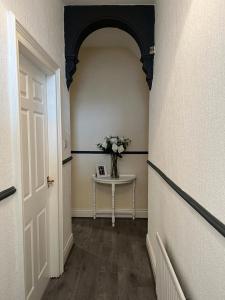 a hallway with a table and a vase of flowers at AA Tyne Apartments in Gateshead