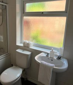 a bathroom with a toilet and a sink and a window at AA Tyne Apartments in Gateshead
