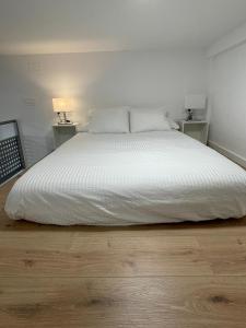- une chambre avec un grand lit blanc et 2 tables de chevet dans l'établissement Miniloft Baiona I, à Baiona