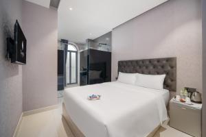a bedroom with a large white bed and a mirror at Mari Hotel By Connek in Ho Chi Minh City