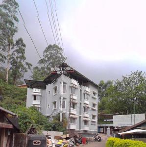 a white hotel with a sign on top of it at Munnar Mount Shelt Hotel in Munnar