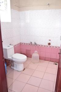 a bathroom with a toilet and pink tiles at Munnar Mount Shelt Hotel in Munnar