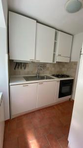 uma cozinha com armários brancos e um lavatório em CasaRemo 