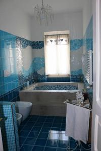 een blauw betegelde badkamer met een bad en een raam bij B&b Sofia in San Nicandro Garganico
