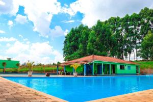 a house with a swimming pool in front of it at Pousada - Pesqueiro do Brasinha in Itamogi