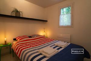 een slaapkamer met een gestreept bed met handdoeken erop bij Vias-Plage - Villa climatisée à 600m de la plage in Vias