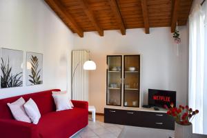 uma sala de estar com um sofá vermelho e uma televisão em CA' GIALLA 5 - sul Lago di Lugano, self check-in e parcheggio - em Cadegliano Viconago