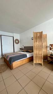 a bedroom with a bed and a wooden partition at Studio bord de mer in Filaos