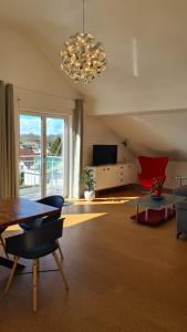 ein Wohnzimmer mit einem Kronleuchter, einem Tisch und Stühlen in der Unterkunft R7 Bodensee mit Seesicht sonnig ruhig groß in Uhldingen-Mühlhofen