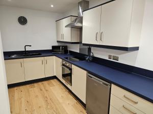 a kitchen with white cabinets and a blue counter top at Spacious, modern 2-bedroom flat in Clifton in Bristol