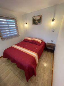 - une chambre avec un lit et une couverture rouge dans l'établissement Cabañas central Lebu, à Lebu