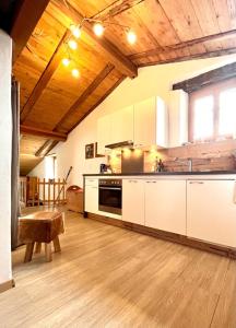 uma cozinha com armários brancos e um tecto de madeira em Augustin Oswald em Müstair