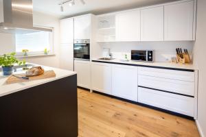 a white kitchen with white cabinets and a wooden floor at Sope Skylodge 08 - Gentuard's & Leandro's Weitblick - Oberried, Schauinsland in Oberried