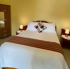 1 dormitorio con 1 cama blanca grande y 2 lámparas en Hostal Restaurant Gocta en Cocachimba
