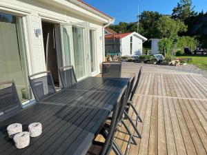 une terrasse en bois avec une table et des chaises sur une maison dans l'établissement Nybyggd villa med närhet till berg och hav, à Hunnebostrand