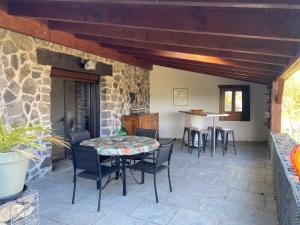 un patio con mesa, sillas y pared de piedra. en Gîte chez Maddy, en Chilhac