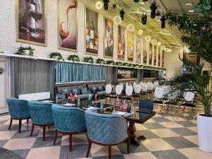 um restaurante com mesas e cadeiras e pinturas na parede em Golden Samarkand Hotel em Samarkand