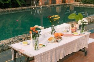 uma mesa com comida e flores junto a uma piscina em Stella Mộc Châu Homestay em Mộc Châu