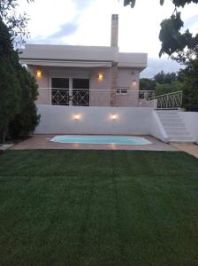 a house with a swimming pool in front of a yard at Cozy villa Vita Lagonisi in Kalívia Thorikoú