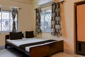 een bed in een kamer met twee ramen bij OYO Florence Guest House And Home Stay in Calcutta