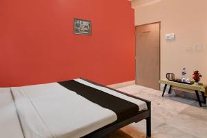 Cama en habitación con pared roja en OYO Florence Guest House And Home Stay, en Calcuta