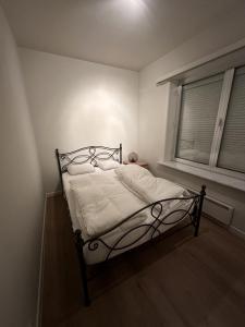 un letto in una stanza bianca con una finestra di Flat centrum Oudenaarde met eigen fietsen berging a Oudenaarde