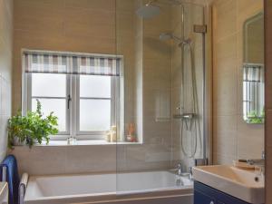 a bathroom with a tub and a window and a sink at Fairholme in Bodfari