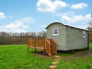 a green tiny house with a bench in a field at Badgers - Uk46750 in Herstmonceux