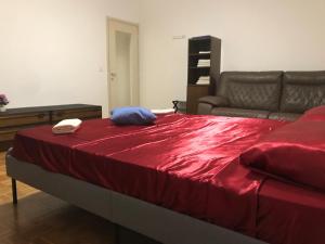 a bedroom with a bed with red sheets and a couch at Pregassona Relaxing Home in Lugano