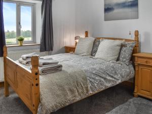 a bedroom with a wooden bed with pillows and a window at New House Farm - Ukc6912 in Leck