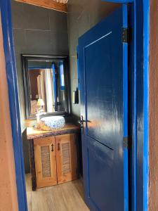 een blauwe deur die leidt naar een badkamer met een wastafel bij Ckoi Atacama Lodge in San Pedro de Atacama