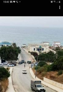 a street with cars driving down a road next to the ocean at Sousou2 in Skikda