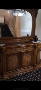 a wooden dresser with a mirror and a piano at Sousou2 in Skikda