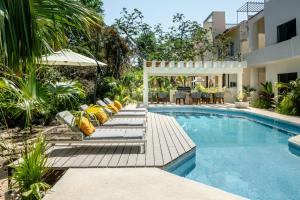 a swimming pool with lounge chairs and a house at Casa Manglar Riviera Maya in Puerto Aventuras