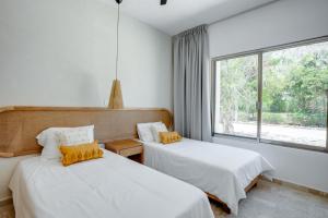 a bedroom with two beds and a large window at Casa Manglar Riviera Maya in Puerto Aventuras
