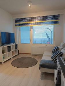 a living room with a couch and a large window at Uusi kaksio parvekkeella ja autopaikalla in Joensuu