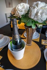 einen Tisch mit einer Flasche Champagner und eine Vase mit Blumen in der Unterkunft Apollo Apartment in Coventry