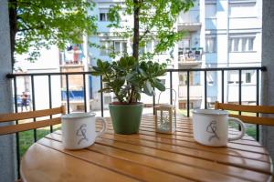 tre tazze da caffè sedute su un tavolo di legno sul balcone di Apartman Vucetic a Kraljevo
