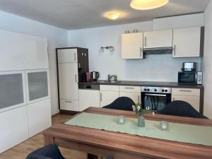 a kitchen with white cabinets and a wooden table with a table sidx sidx at apart belmonte in Wald am Arlberg