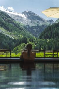 una donna seduta in piscina con vista sulle montagne di Alpinhotel Berghaus spa a Tux