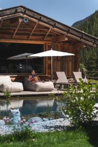 a woman sitting on a couch next to a pool at Alpinhotel Berghaus spa in Tux