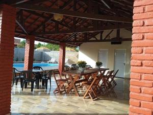 een patio met houten tafels en stoelen en een bakstenen muur bij Casa com piscina in Andirá