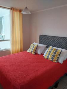 Un dormitorio con una cama roja con almohadas y una ventana en Departamento Peñuelas Sol Marina III La Serena - Coquimbo, en Coquimbo
